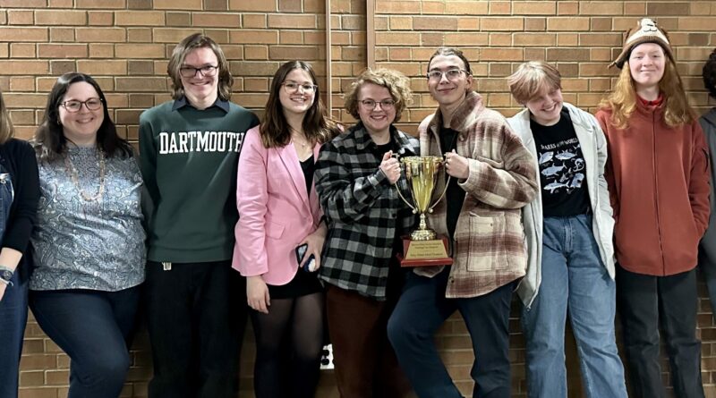 Caption: The Central debate team and coaches celebrate with their Challenge Cup Trophy