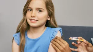 Young girl about to receive a vaccine in her upper arm.