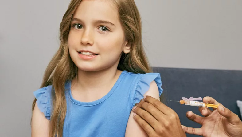 Young girl about to receive a vaccine in her upper arm.