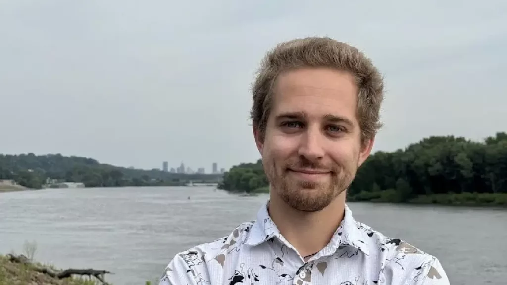 Adam Dullinger poses in front of a body of water