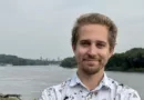 Adam Dullinger poses in front of a body of water