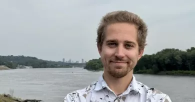 Adam Dullinger poses in front of a body of water
